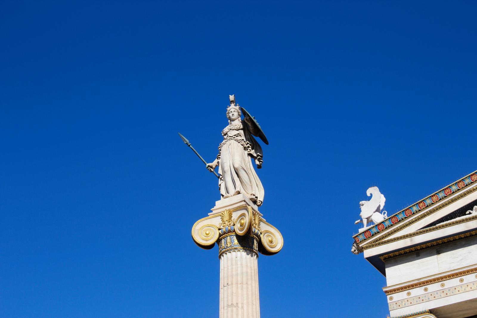 A statue of the goddess Athena stands against a clear blue sky.